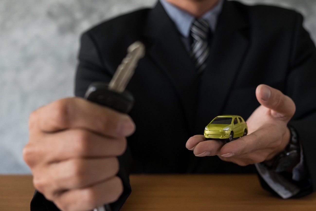 hombre sujetando unas llaves, con un coche en la mano